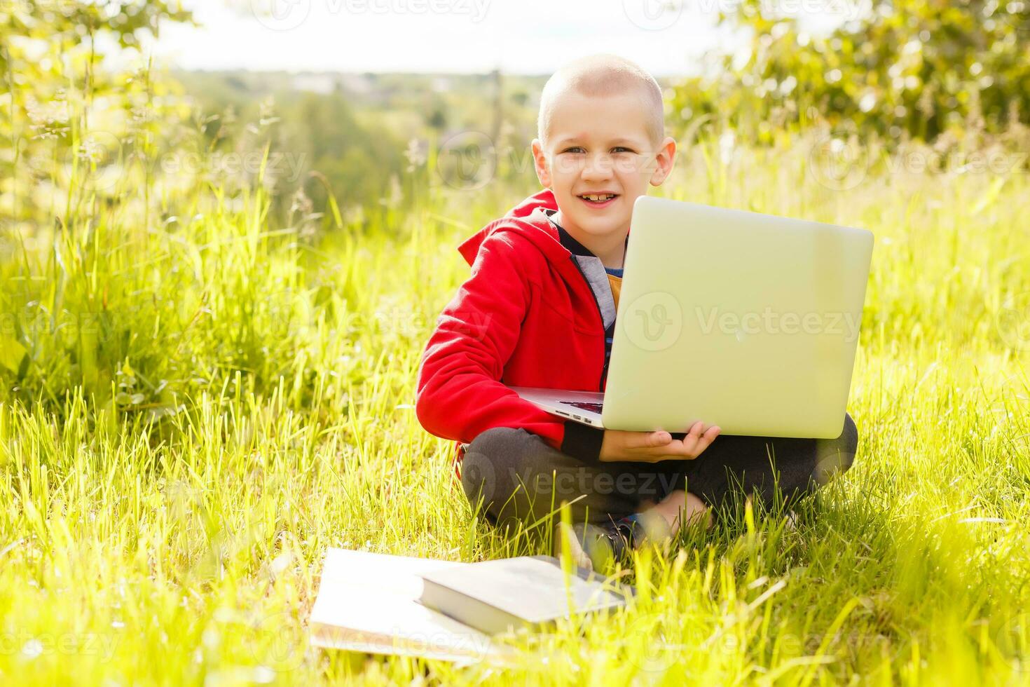 Distance learning. Boy learns autdoor laptop. Doing homework on grass. The child learns in the fresh air. The child's hands and computer photo