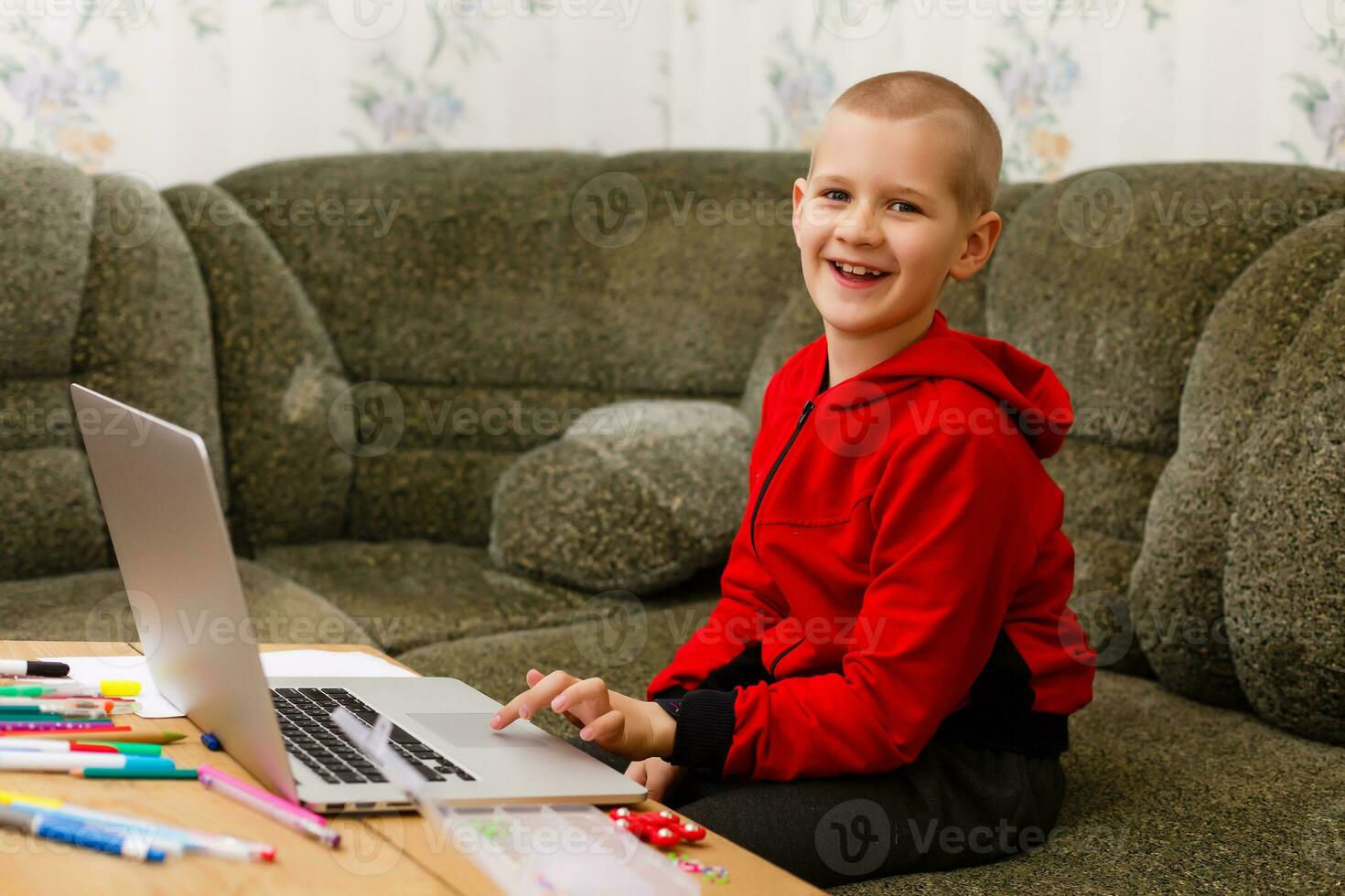 Happy boy sitting at his desk With laptop computer photo