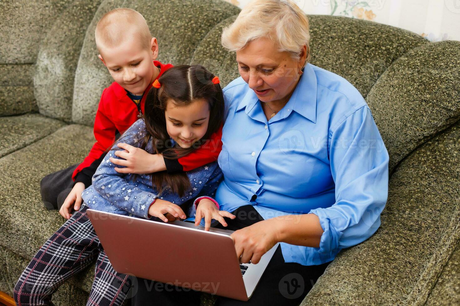 Grandmother with grandchildren using laptop at home photo