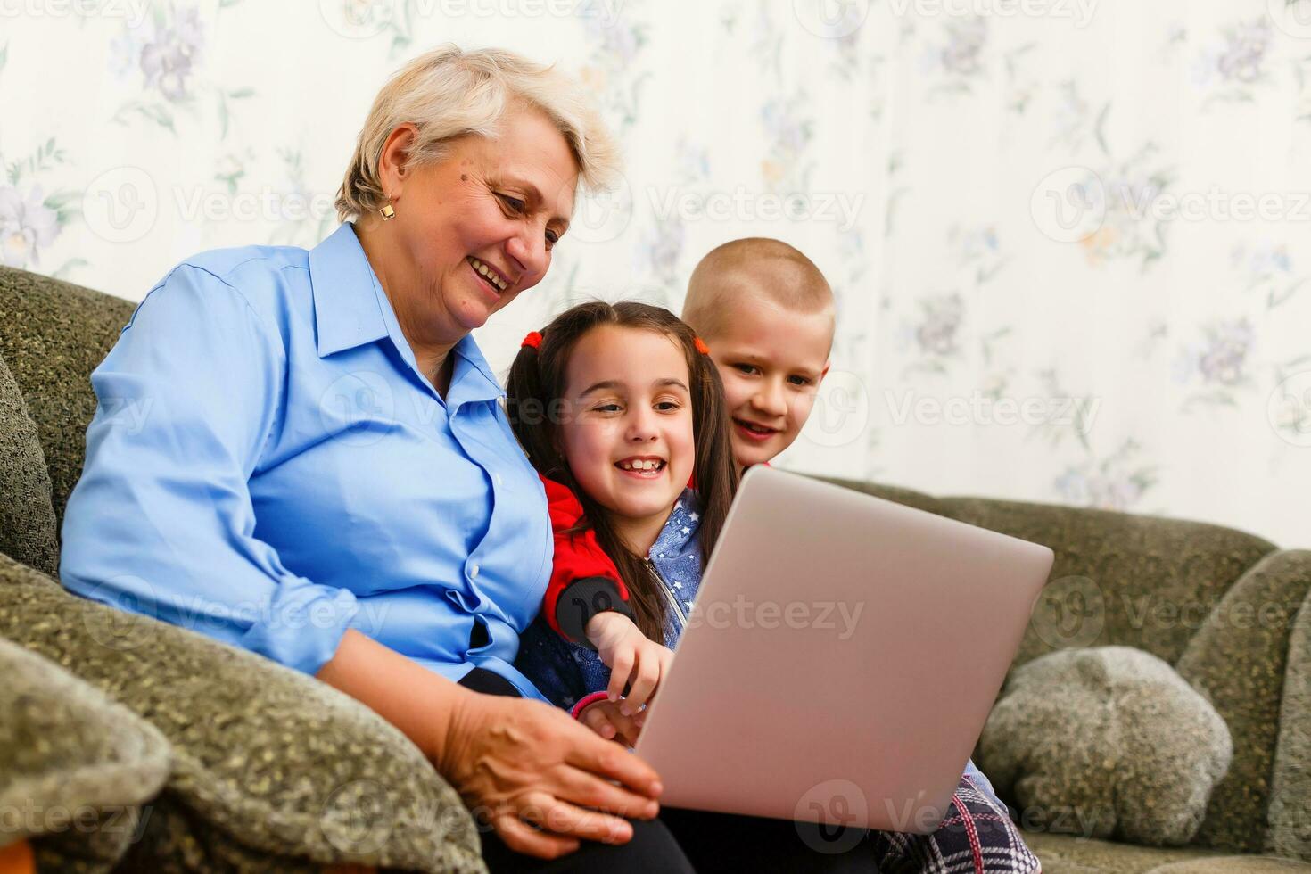 Grandmother with grandchildren using laptop at home photo