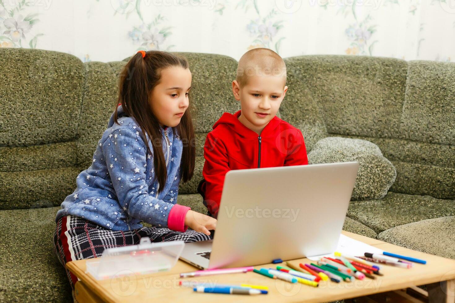 Two beautiful cute happy smiling children, a boy and a girl, use laptop for distance learning or entertainment. photo