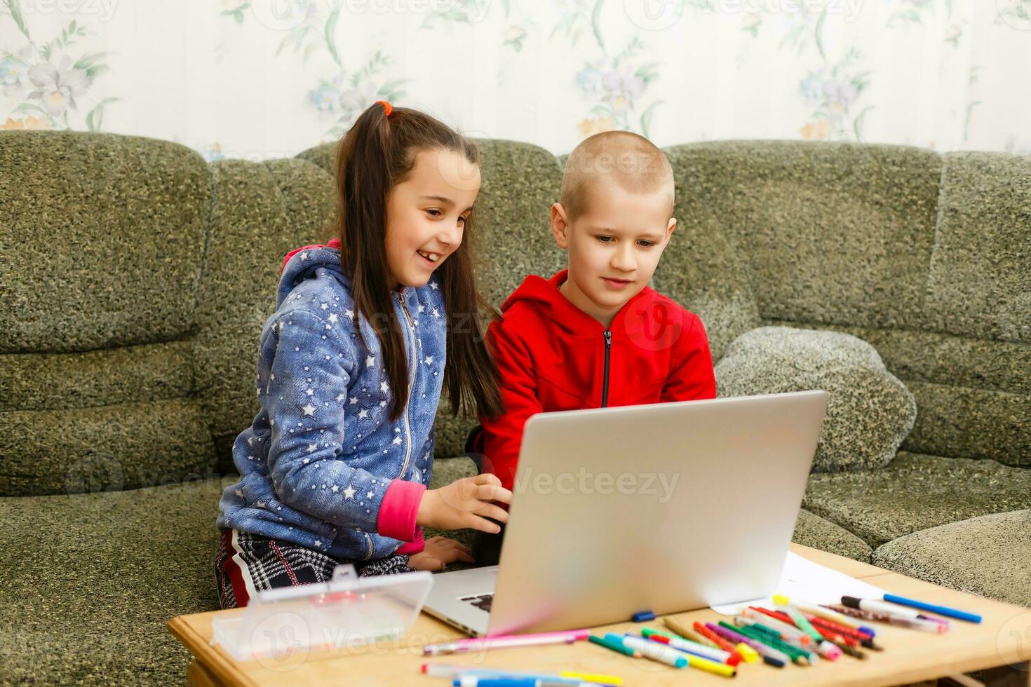 Two beautiful cute happy smiling children, a boy and a girl, use laptop for distance learning or entertainment. photo