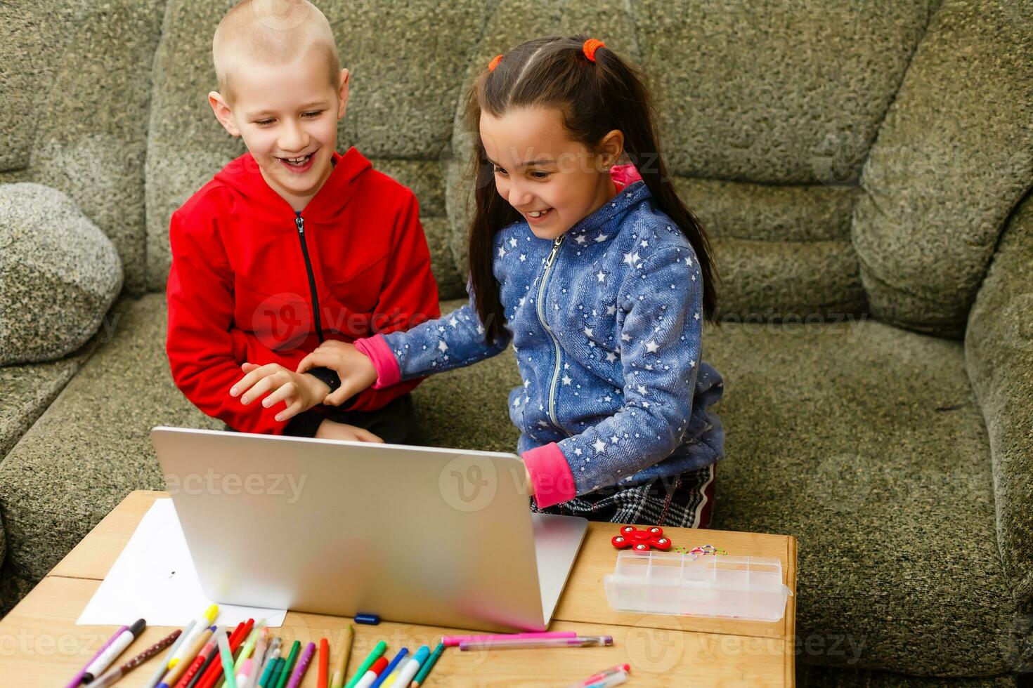Two beautiful cute happy smiling children, a boy and a girl, use laptop for distance learning or entertainment. photo