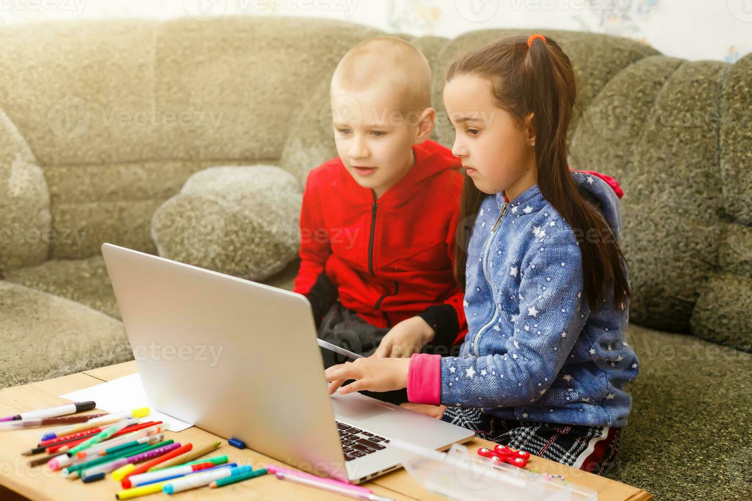 Two beautiful cute happy smiling children, a boy and a girl, use laptop for distance learning or entertainment. photo