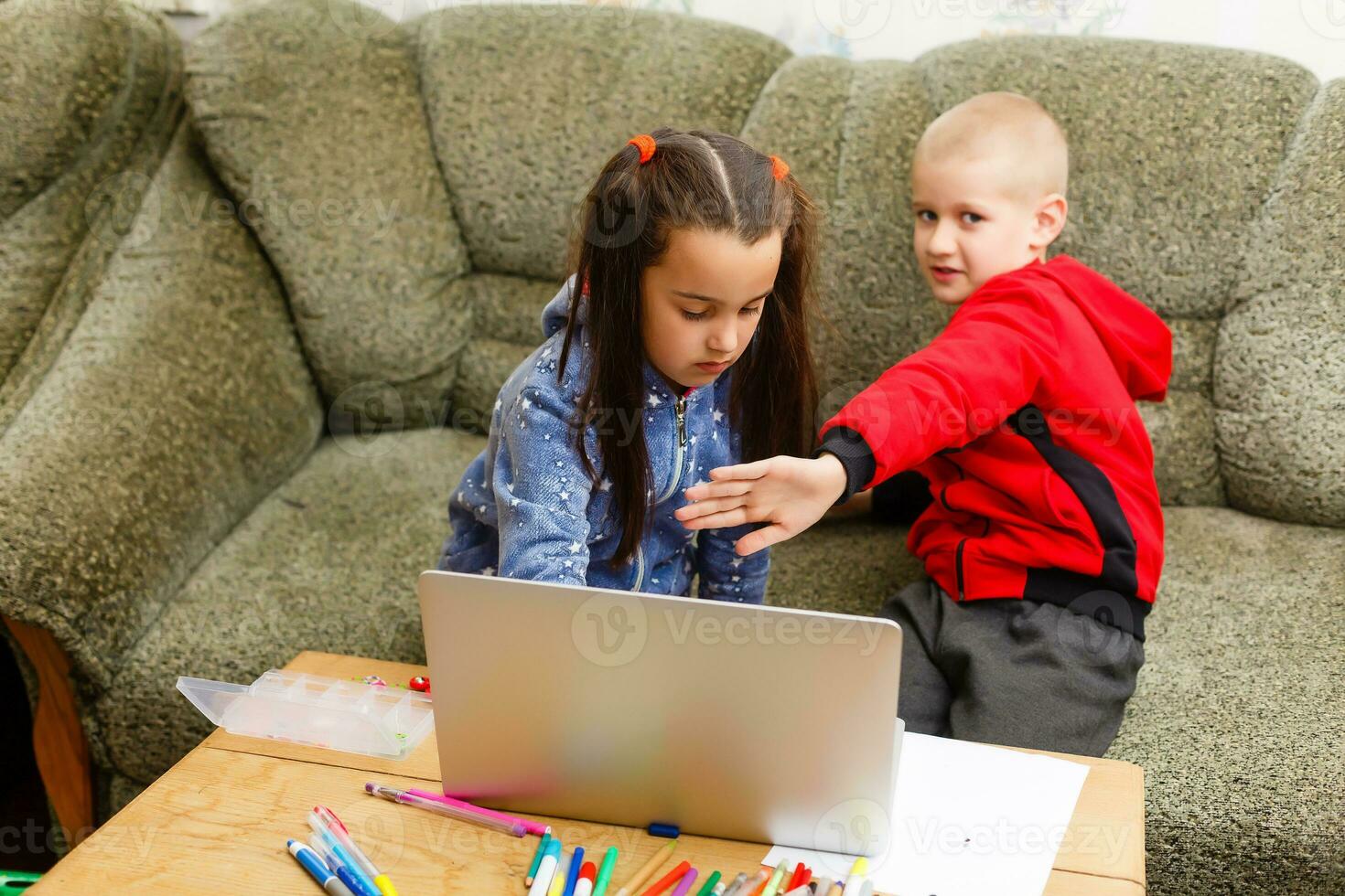 Two beautiful cute happy smiling children, a boy and a girl, use laptop for distance learning or entertainment. photo