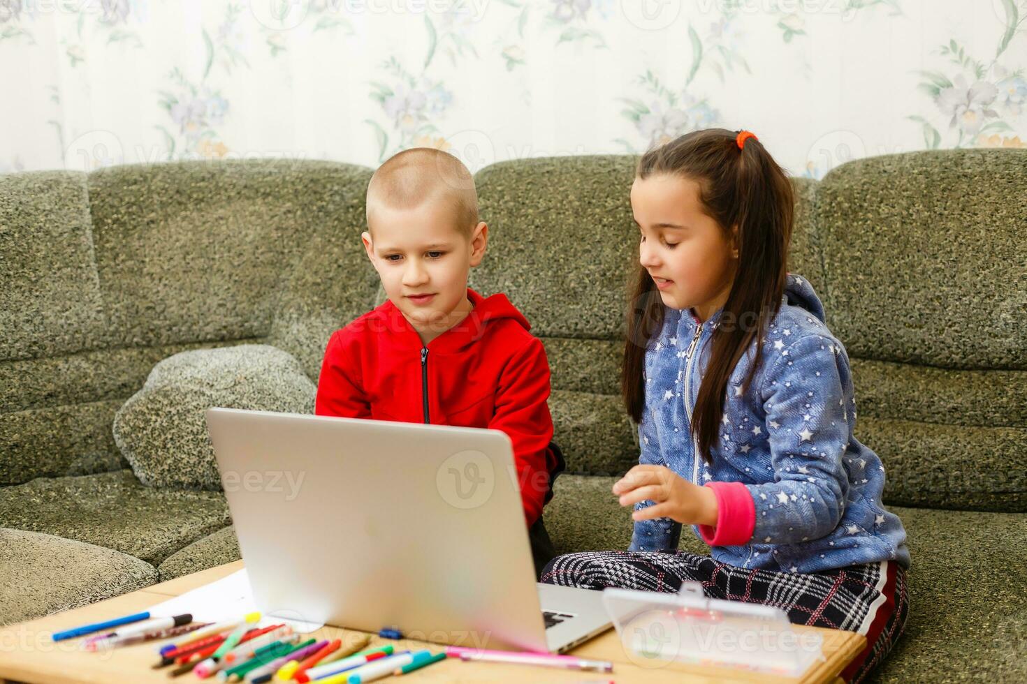 distancia aprendizaje en línea educación. colegio chico y niña estudiando a hogar con ordenador portátil cuaderno y haciendo tarea. sentado a un mesa foto