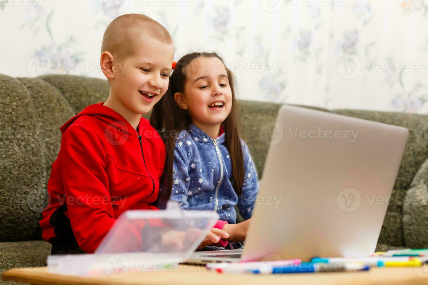 Two beautiful cute happy smiling children, a boy and a girl, use laptop for distance learning or entertainment. photo