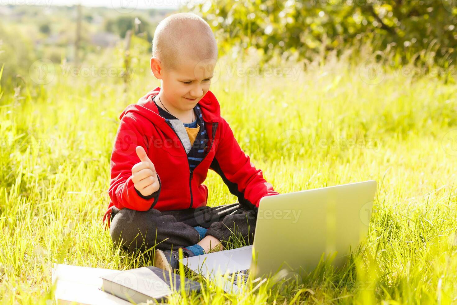 Distance learning. Boy learns autdoor laptop. Doing homework on grass. The child learns in the fresh air. The child's hands and computer photo