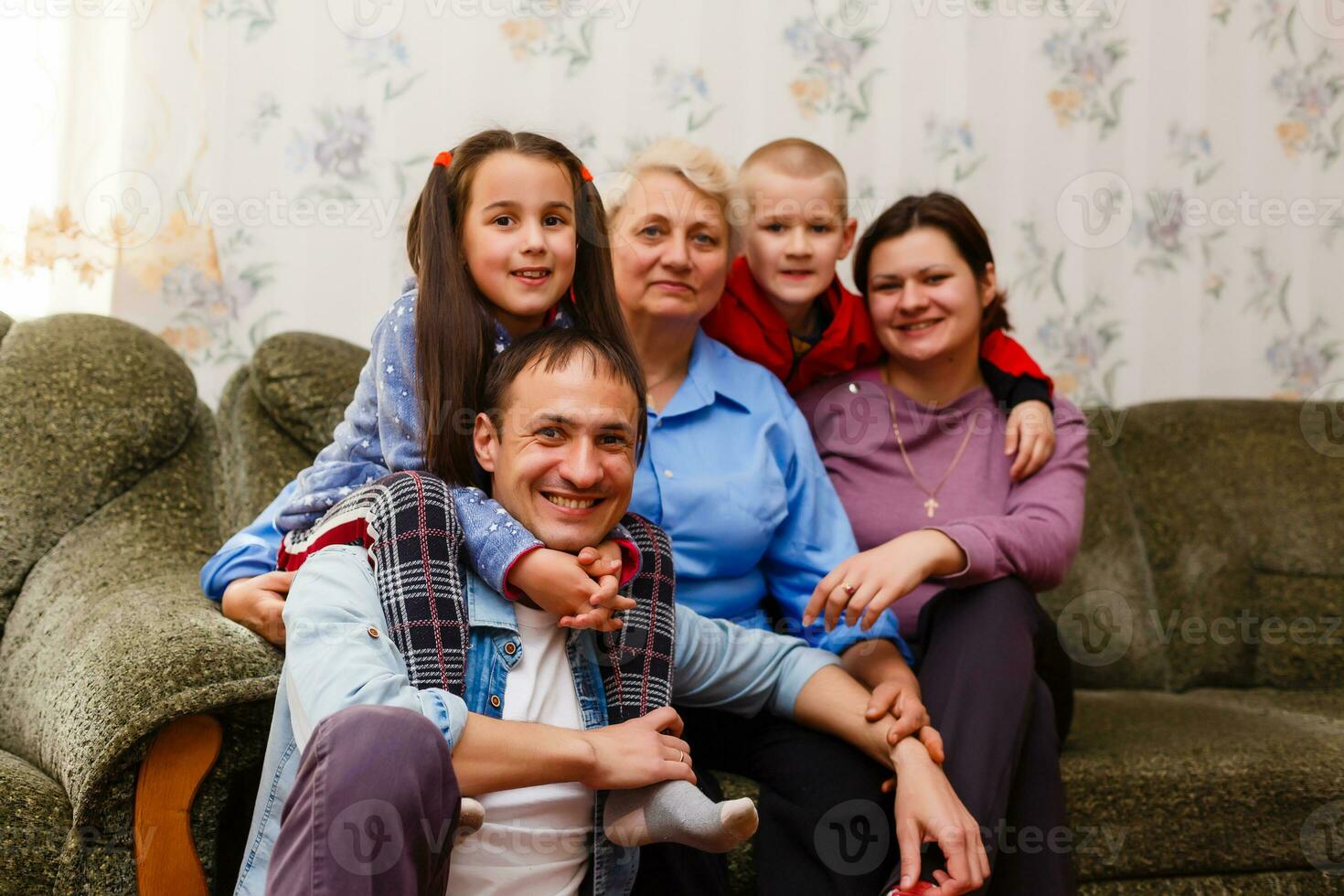 Grandmother and grandchildren sitting together on sofa in living room photo