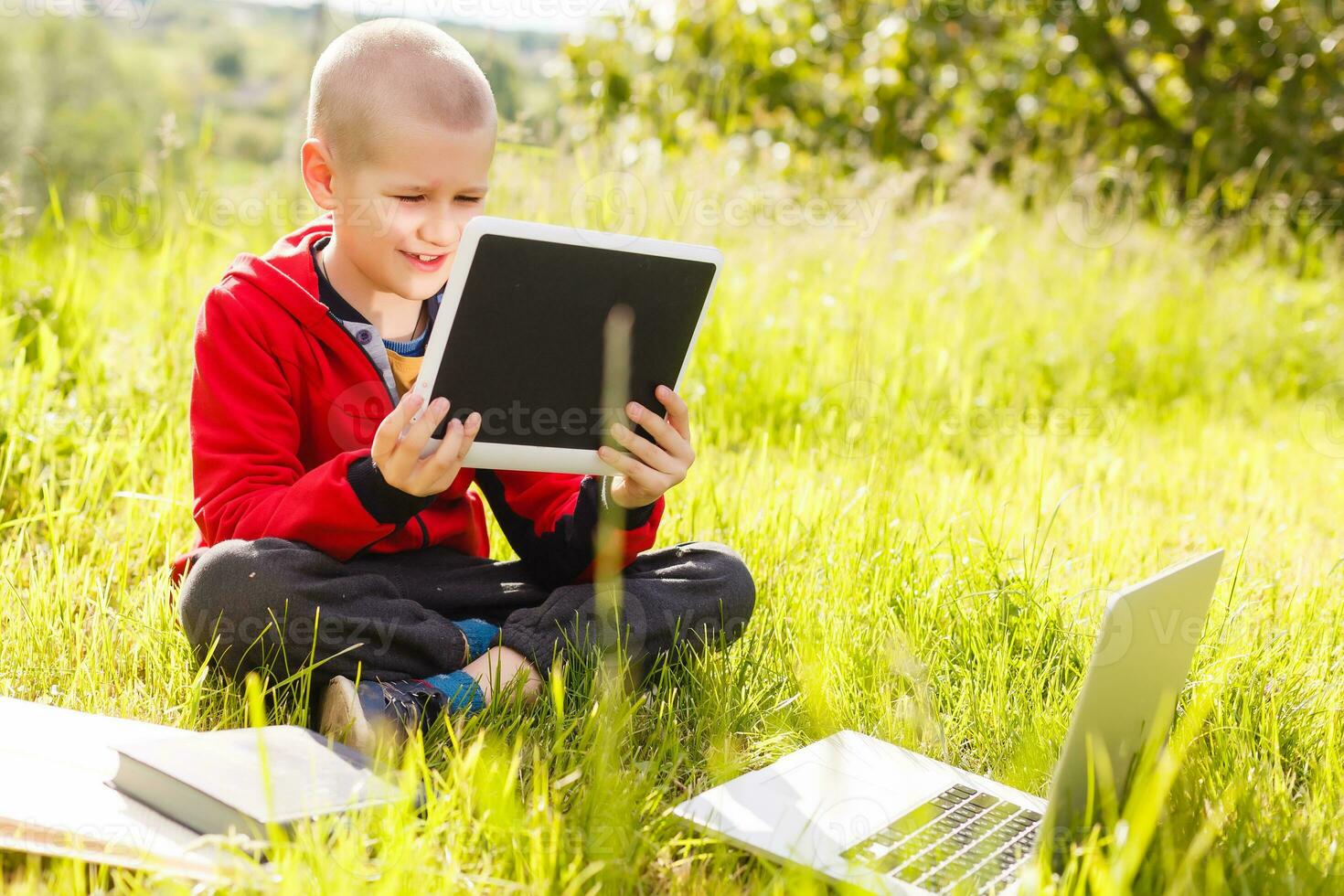 Distance learning. Boy learns autdoor laptop. Doing homework on grass. The child learns in the fresh air. The child's hands and computer photo
