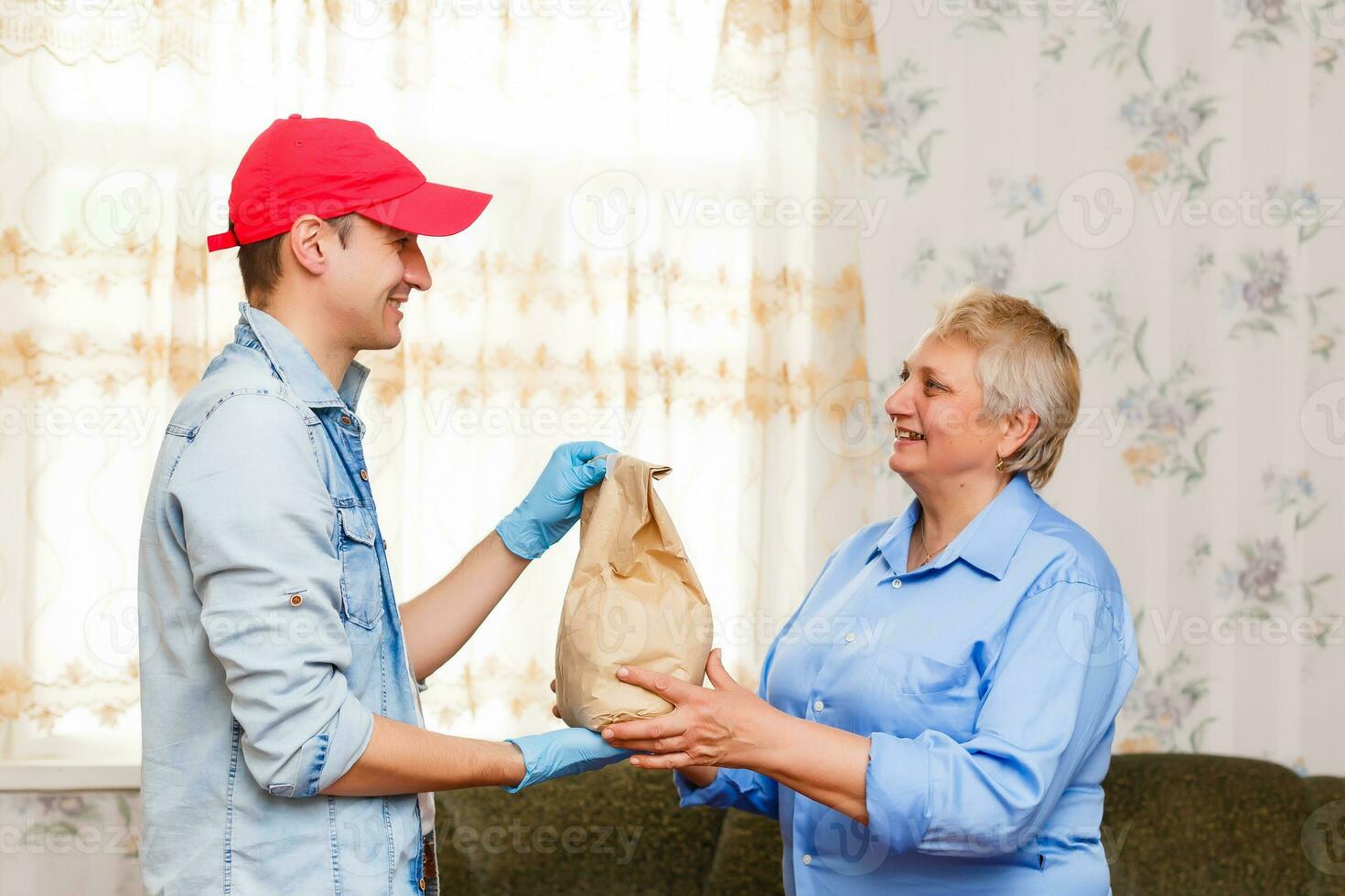 An elderly woman stays at home. Food delivery in a medical mask. photo