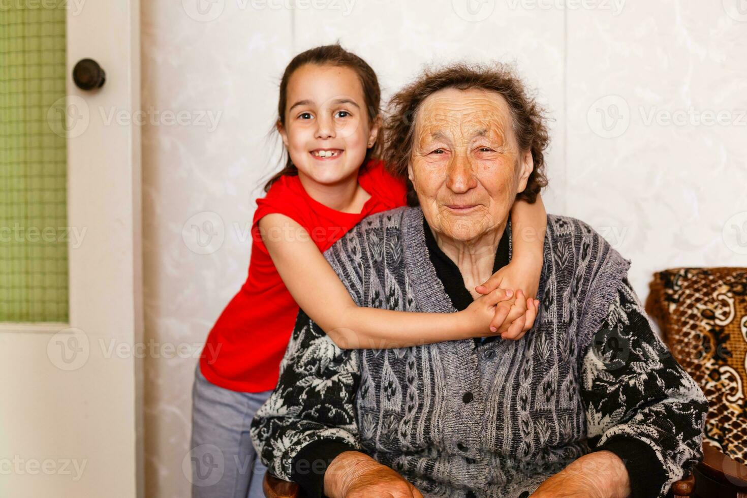 Senior woman hugging granddaughter while sitting on sofa at home photo