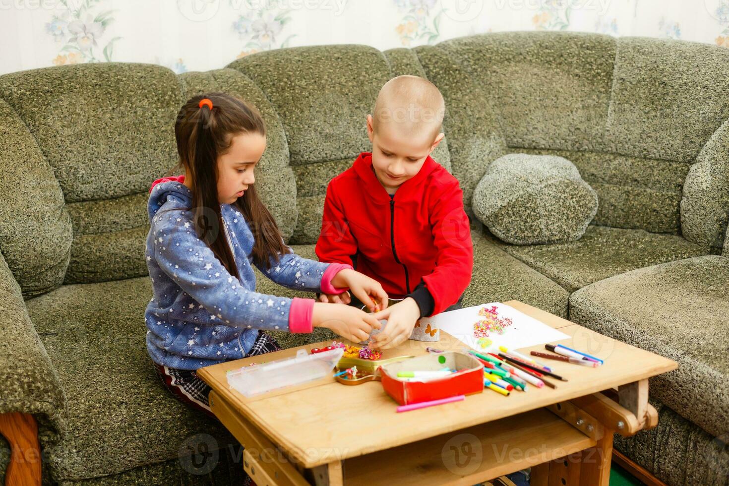 primary school children boy and girl are engaged in creative hand-made art at the table at home photo