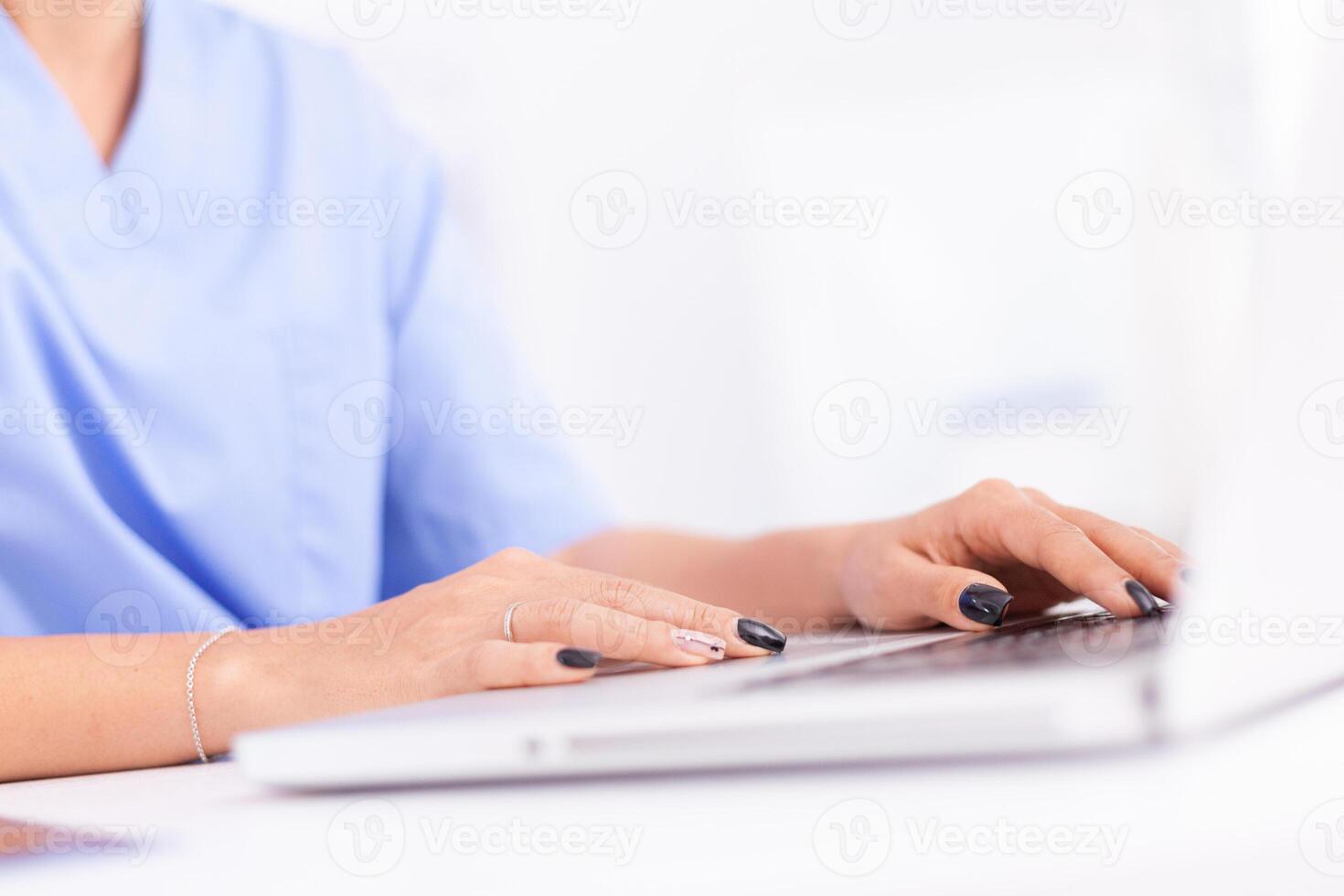 Close up of physician in hospital office typing patient diagnosis. Health practitioner searching in hospital database using laptop in hospital cabinet, keyboard, job. photo