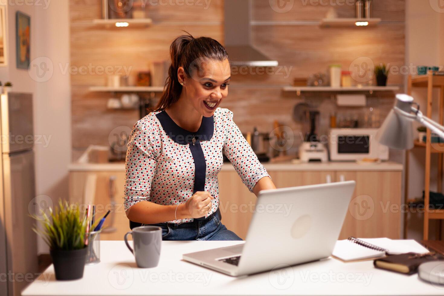 Excited businesswoman after receiving good news on eamil working late at night in home. Employee using modern technology at midnight doing overtime for job, business, busy, career, network, lifestyle. photo