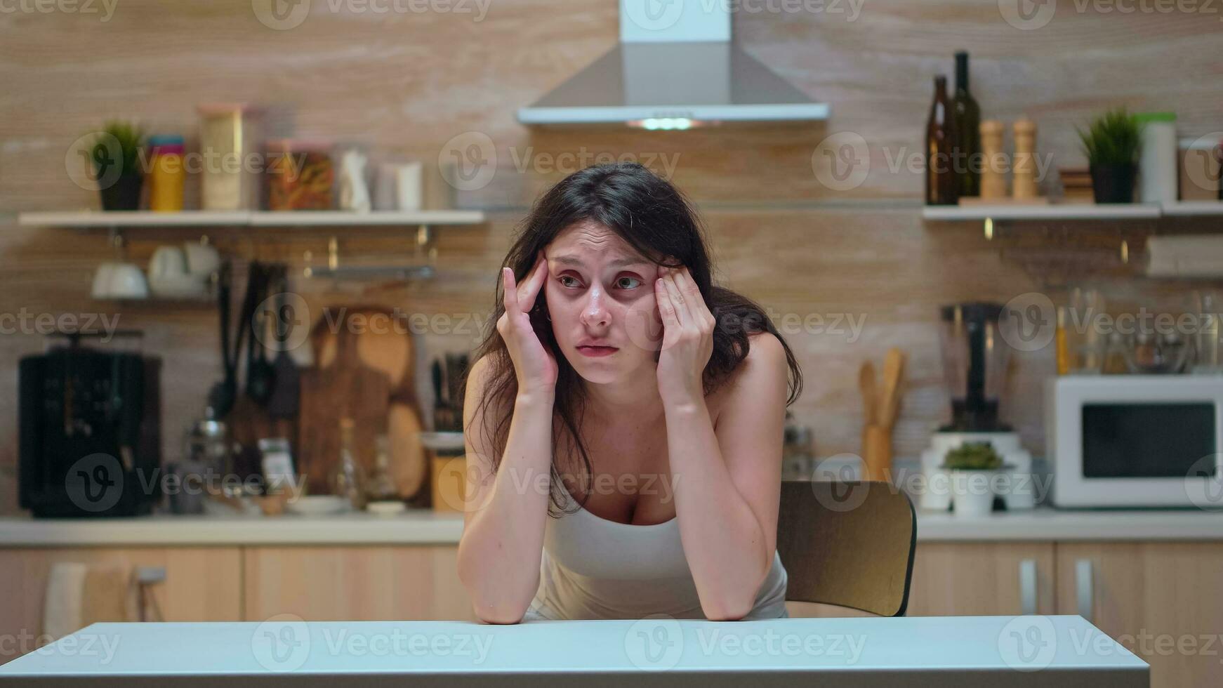 Woman with headache sitting on the chair massaging temples. Stressed tired unhappy worried unwell wife suffering of migraine, depression, disease and anxiety feeling exhausted with dizziness symptoms photo