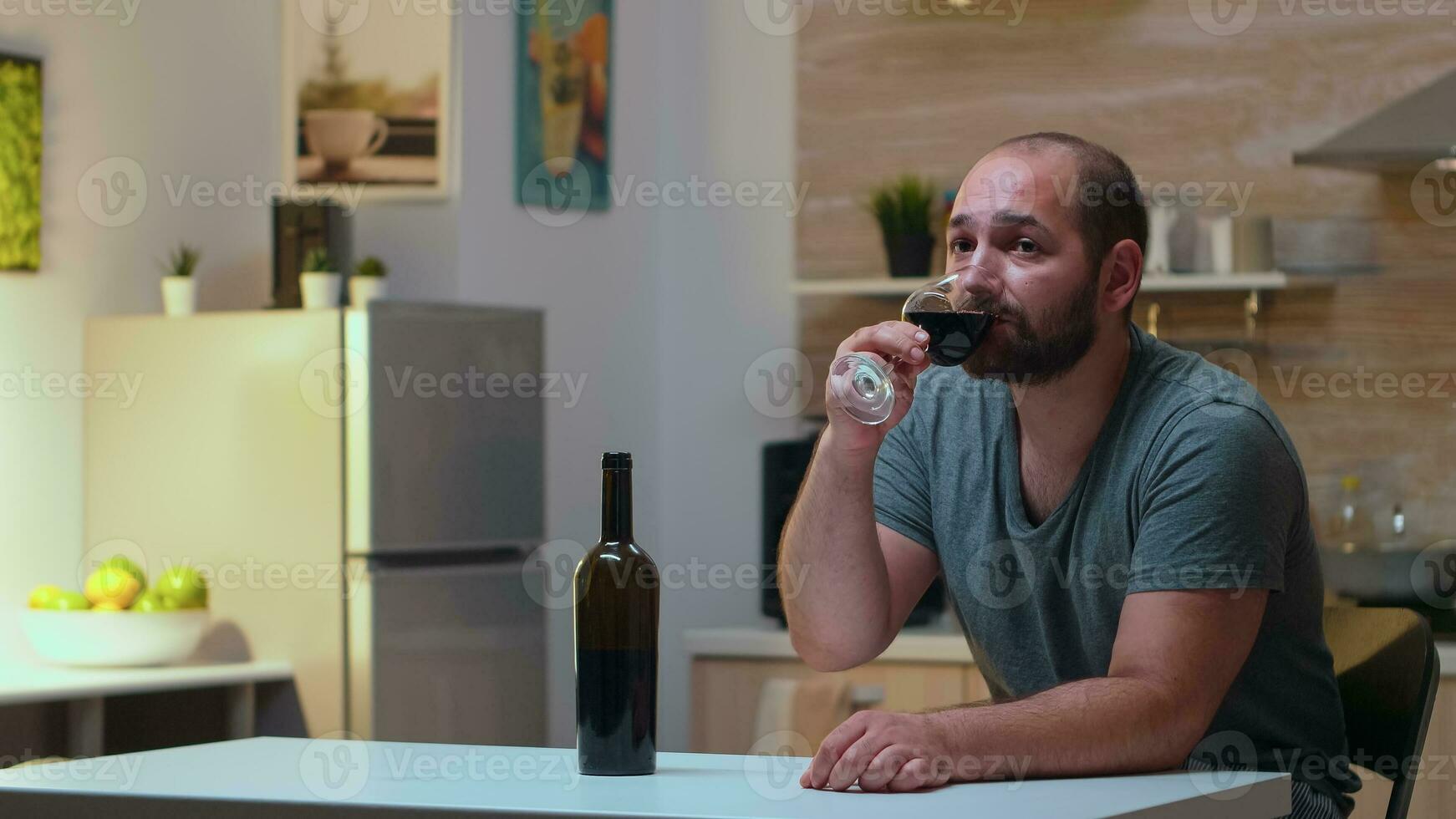 Lonely husband drinking a glass of wine at home. Unhappy person suffering of migraine, depression, disease and anxiety feeling exhausted with dizziness symptoms having alcoholism problems. photo