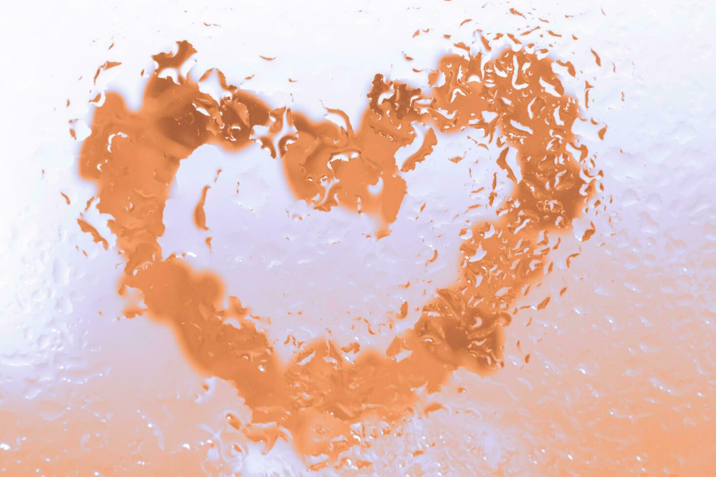 Peach Fuzz heart under glass surface with water drops close. Valentines background, photo