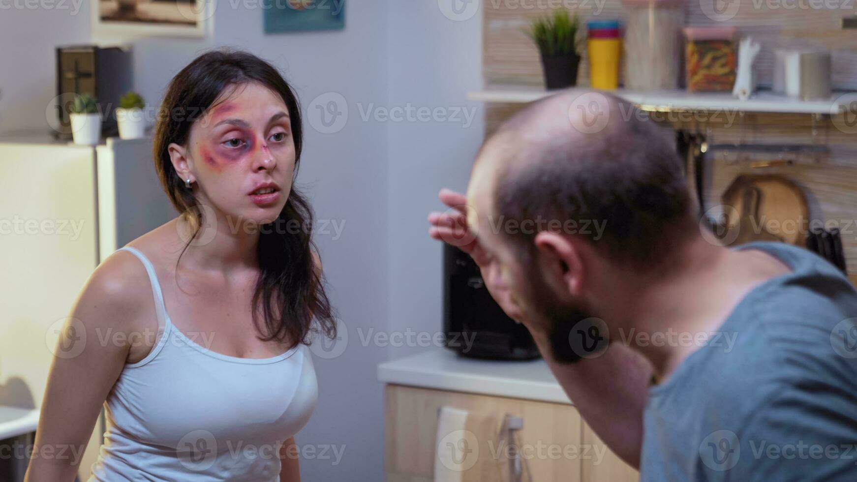 Traumatised woman yelling at drunk man holding a bottle of wine. Abused terrified beaten wife covered in bruises suffering injury from alcoholic violent brutal aggressive husband screeming, fighting. photo