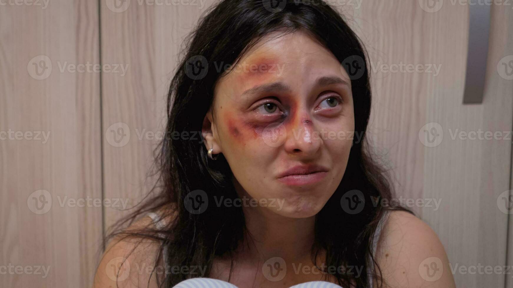 Abused wife crying and drinking sitting on the floor while drunk man is sleeping. Alcoholic aggressive husband abusing injuring terrified helpless, afraid, beaten and panicked wife living in terror. photo