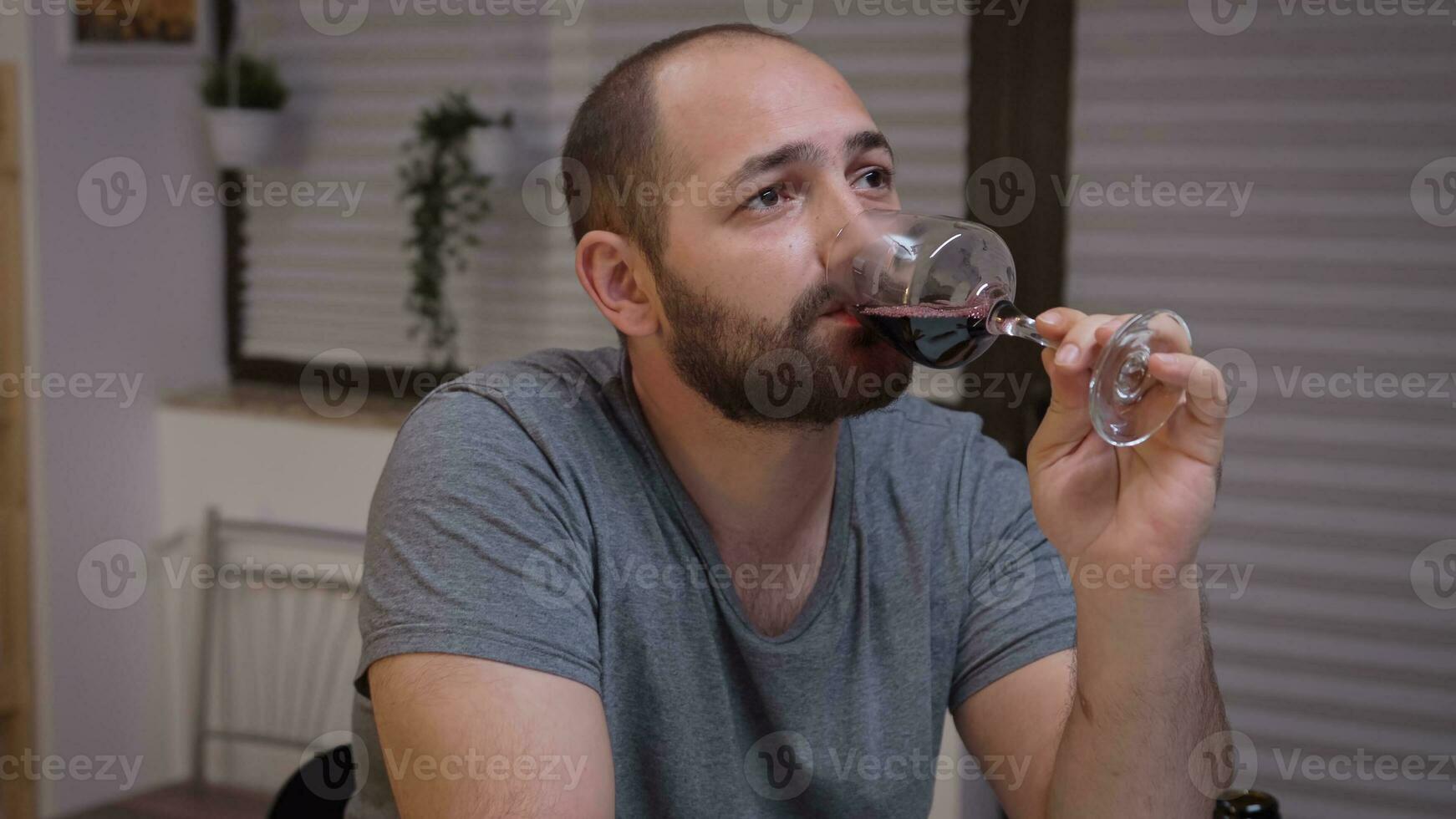 Depressed man drinking alone in the kitchen. Unhappy person suffering of migraine, depression, disease and anxiety feeling exhausted with dizziness symptoms having alcoholism problems. photo