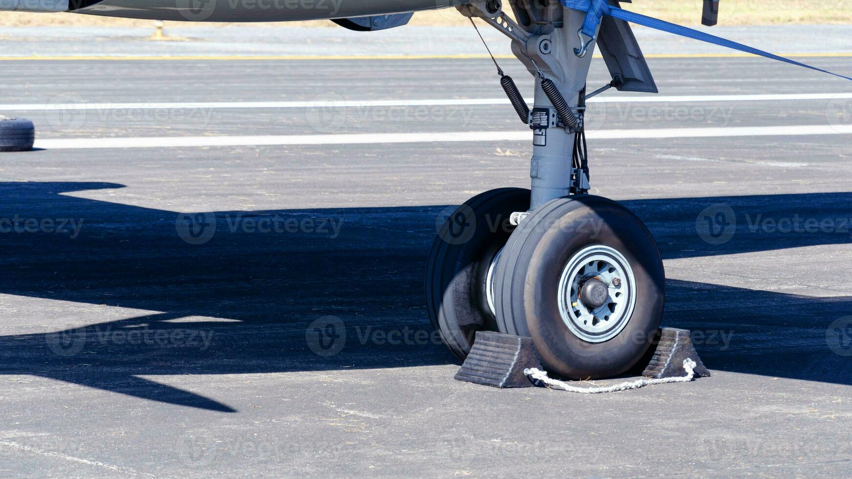 Close-up of front wheels of airplane with chock, Airplane parked at the airport, aircraft undercarriage. Detail of nose wheel. photo