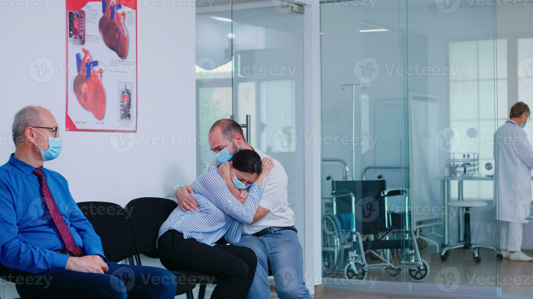 Unfavorable news from doctor to young couple in hospital waiting area during corona virus outbreak. Husband and wife wearing face mask against infection with covid 19. photo