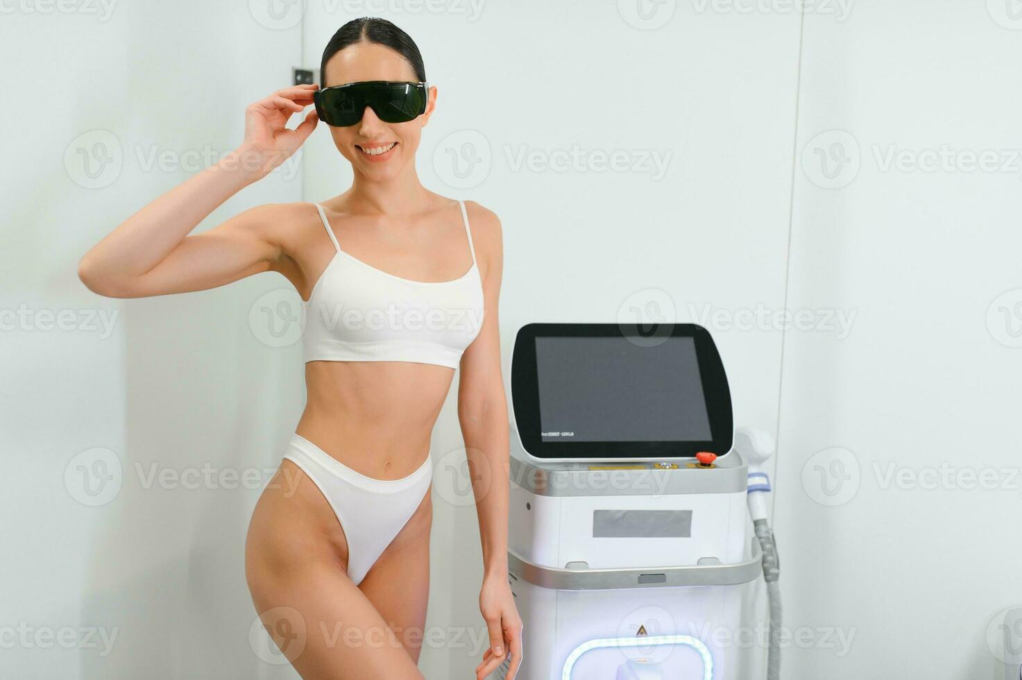 Happy woman near the laser hair removal machine. Beauty studio photo