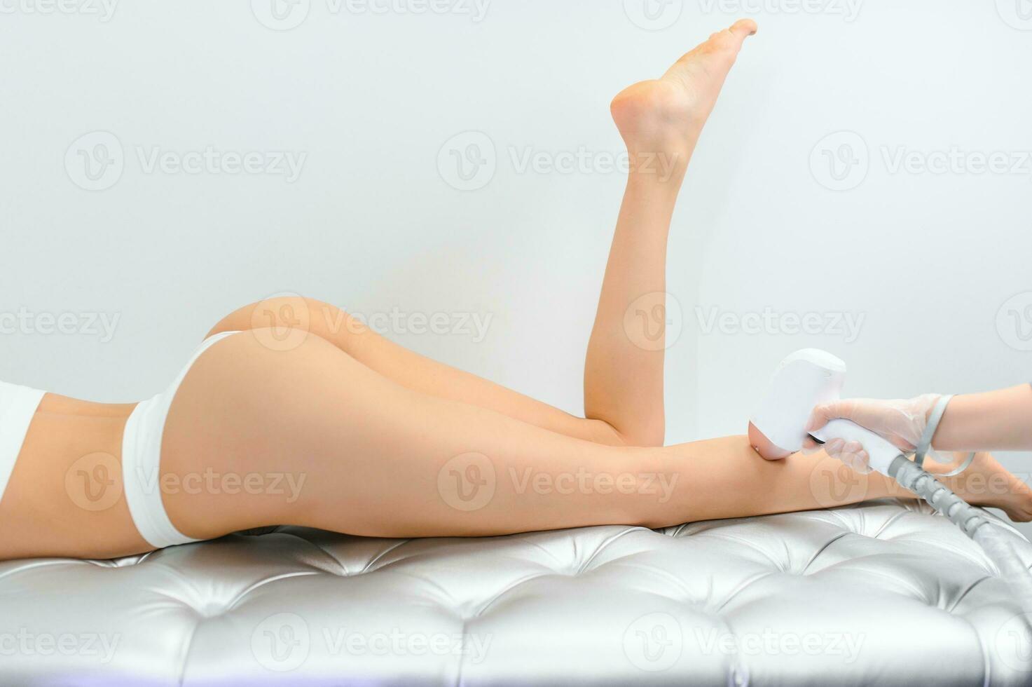 Young woman making body hair removal laser depilation in beauty center photo