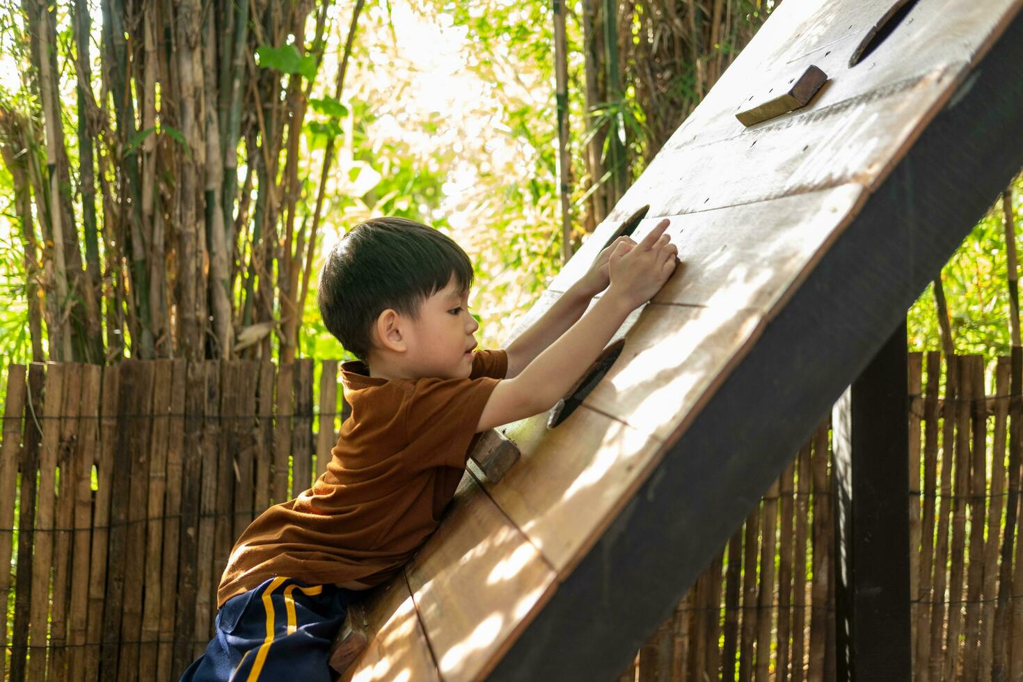 Little Asian boy playing children's sports equipment outdoors photo