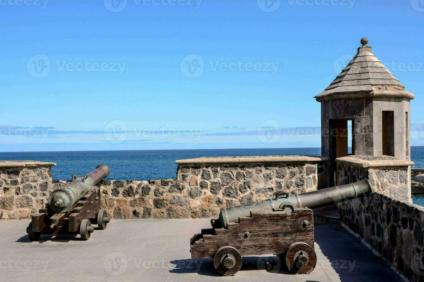 two cannons on the wall of a castle overlooking the ocean photo