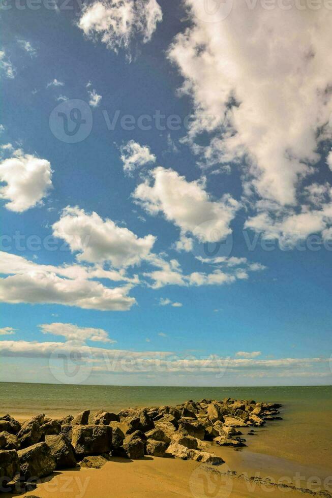 a beach with rocks and water under a blue sky photo