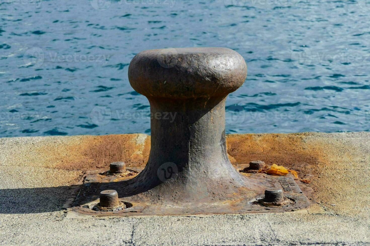 a metal cleat on a pier near the water photo