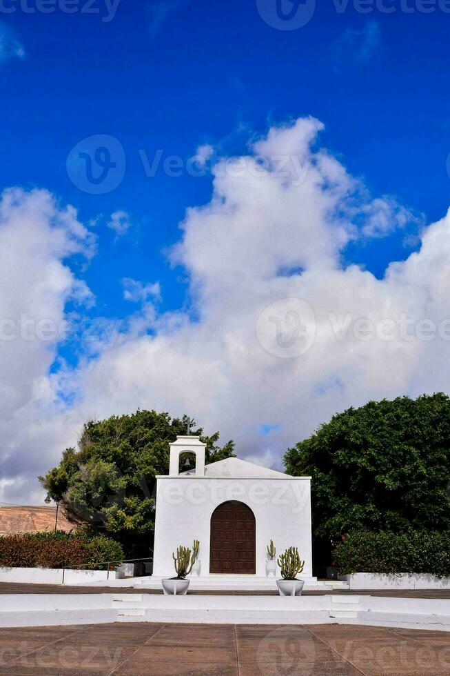 a white church with a blue sky and clouds photo