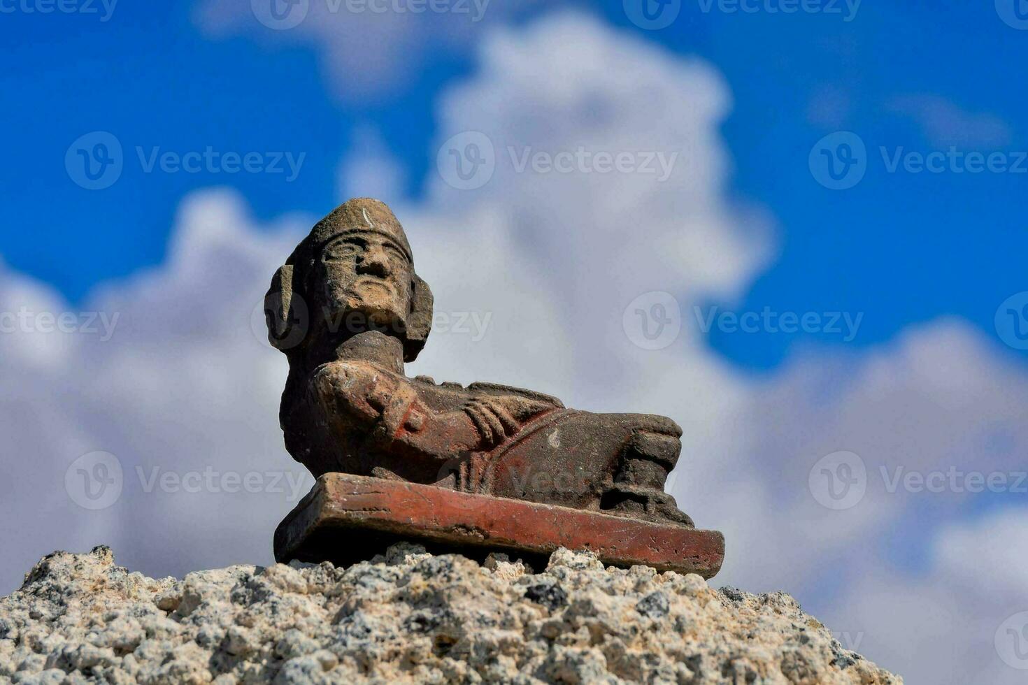 ancient mexican statue of a man sitting on a rock photo