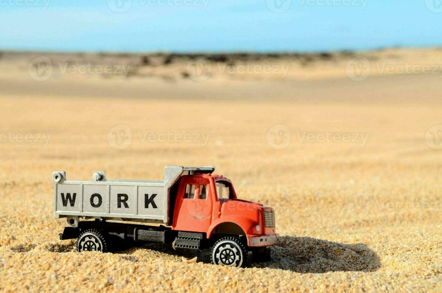 a toy truck with the word work on it is sitting in the sand photo