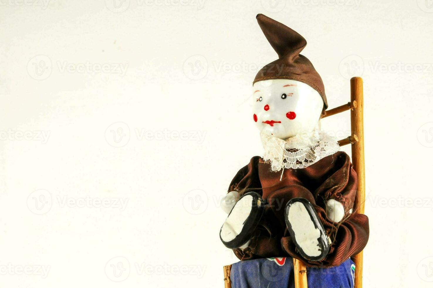 a small doll sitting on a wooden chair photo