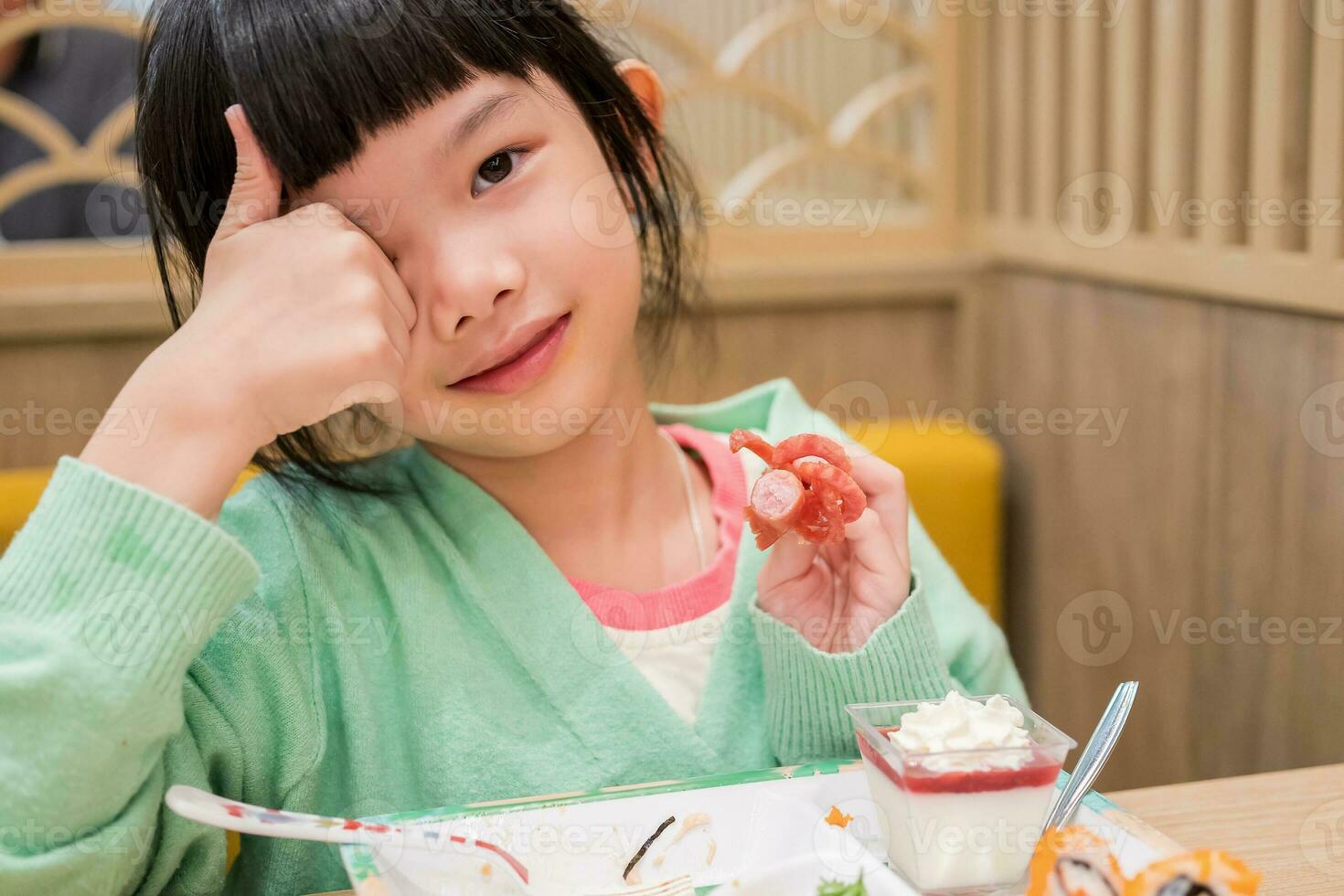 linda pequeño asiático niño niña comiendo comida foto