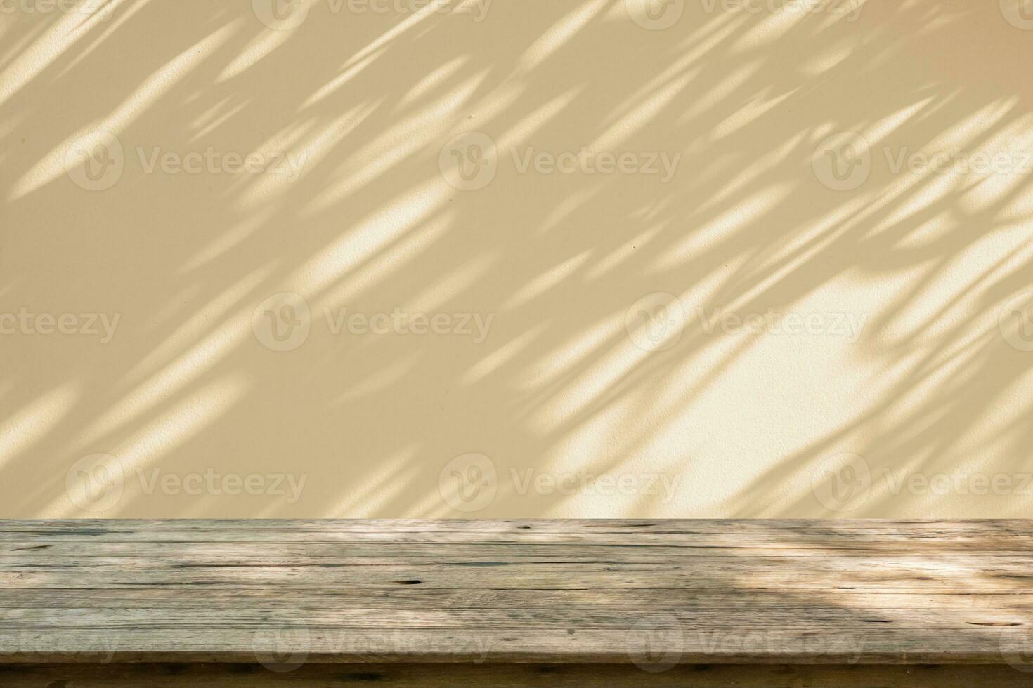 Empty wood table top on beige wall texture with tree leaves shadow background photo