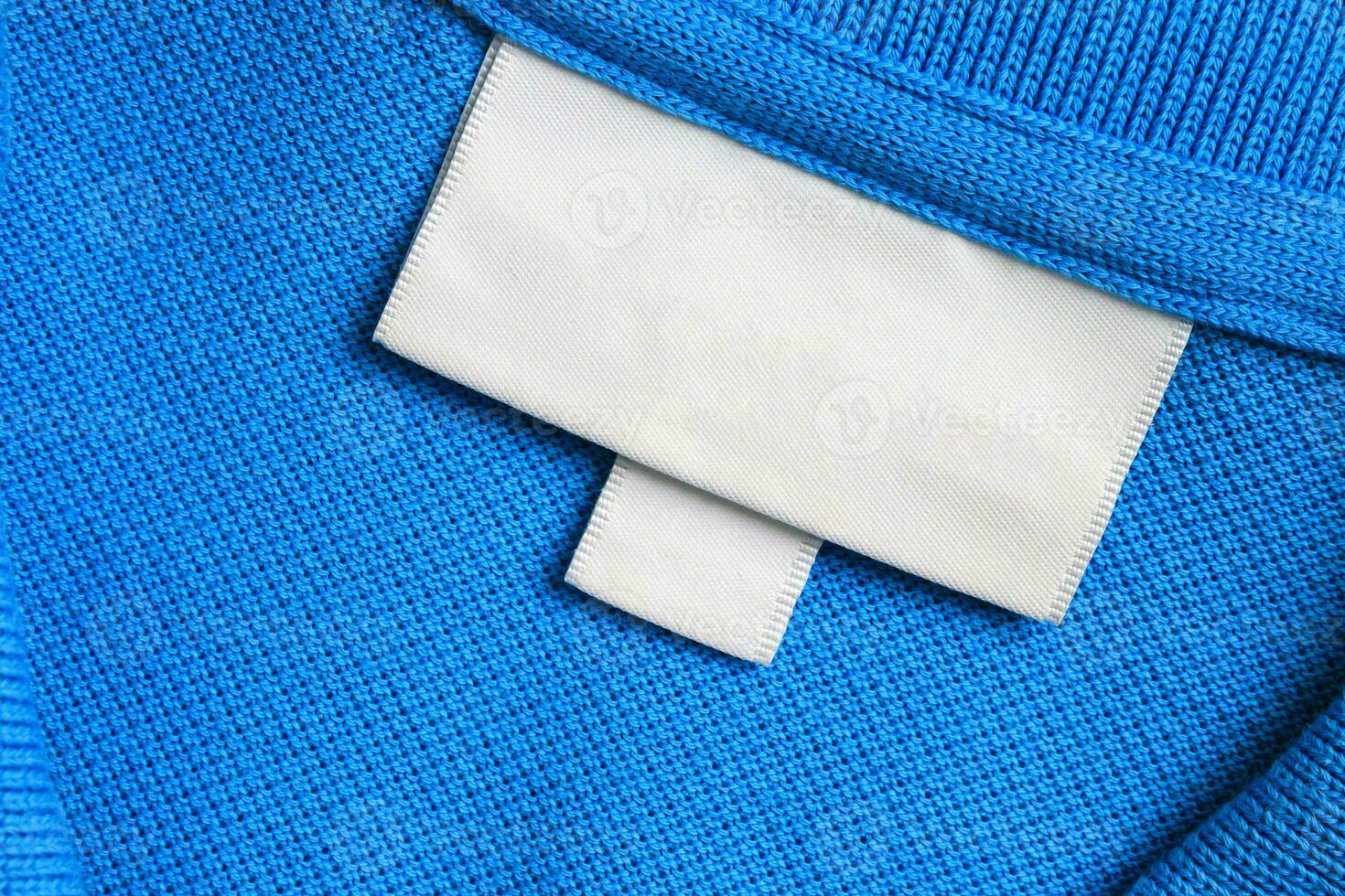 Blank white laundry care clothes label on blue shirt fabric texture background photo