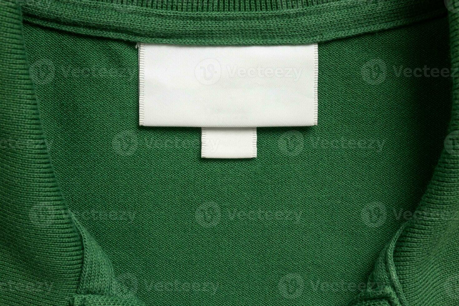 Blank white laundry care clothes label on green shirt fabric texture background photo