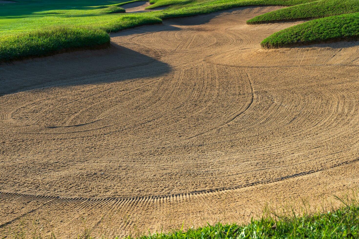 Golf Course Sand Pit Bunkers, green grass surrounding the beautiful sand holes is one of the most challenging obstacles for golfers and adds to the beauty of the golf course. photo