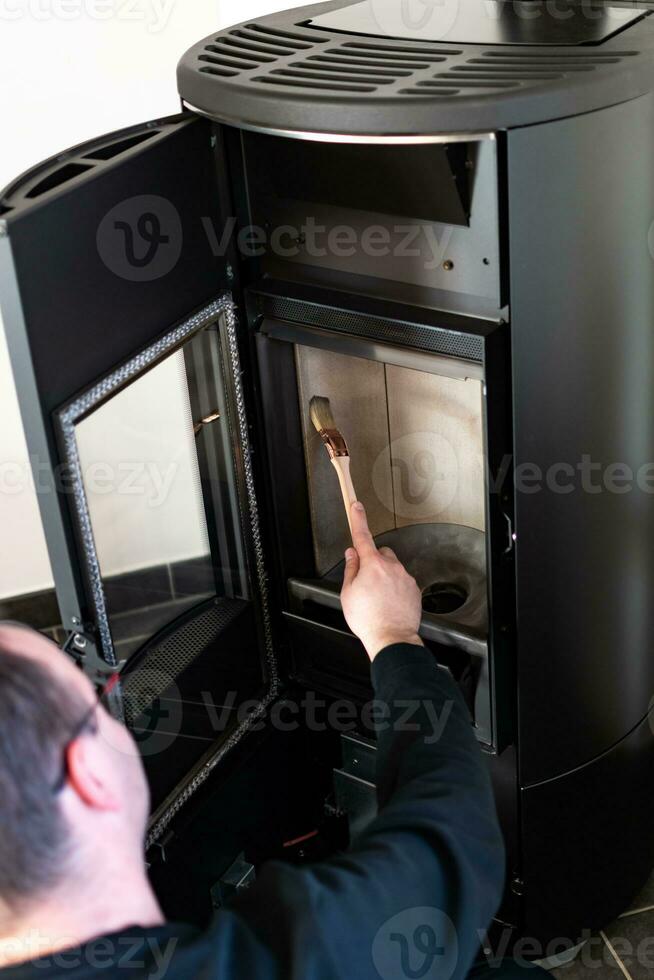 Man cleaning pellet stove with brush photo