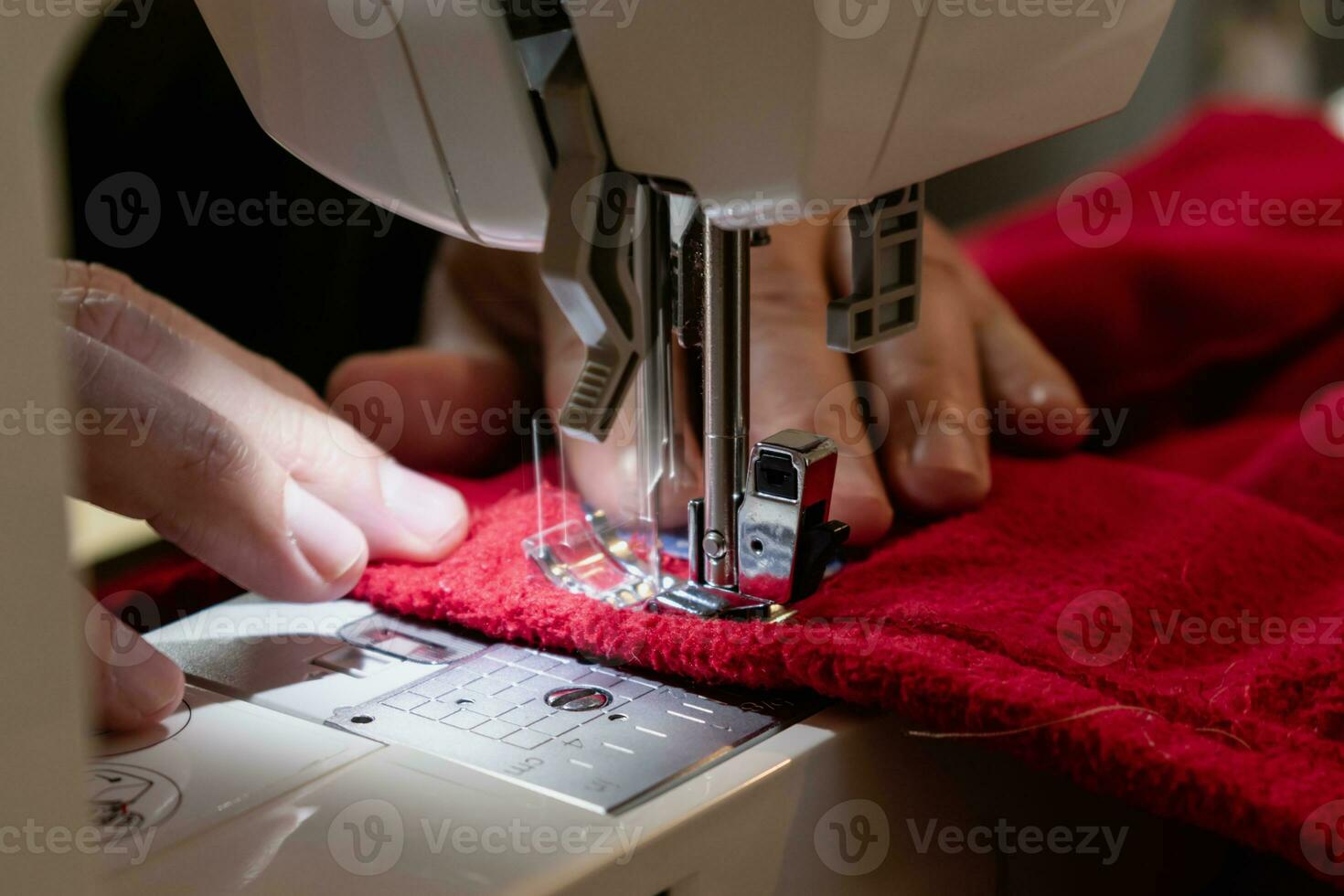 Man using a sewing machine with a red garment, for repair work, customization, creation, upcycling photo