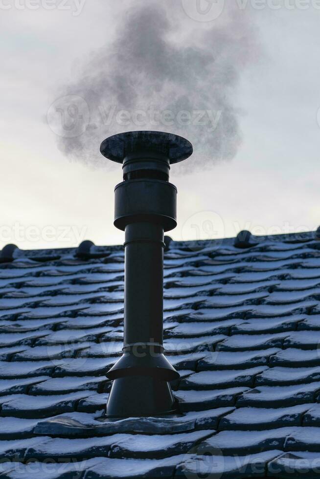 Chimney of a wood or pellet stove installed on the roof with smoke photo