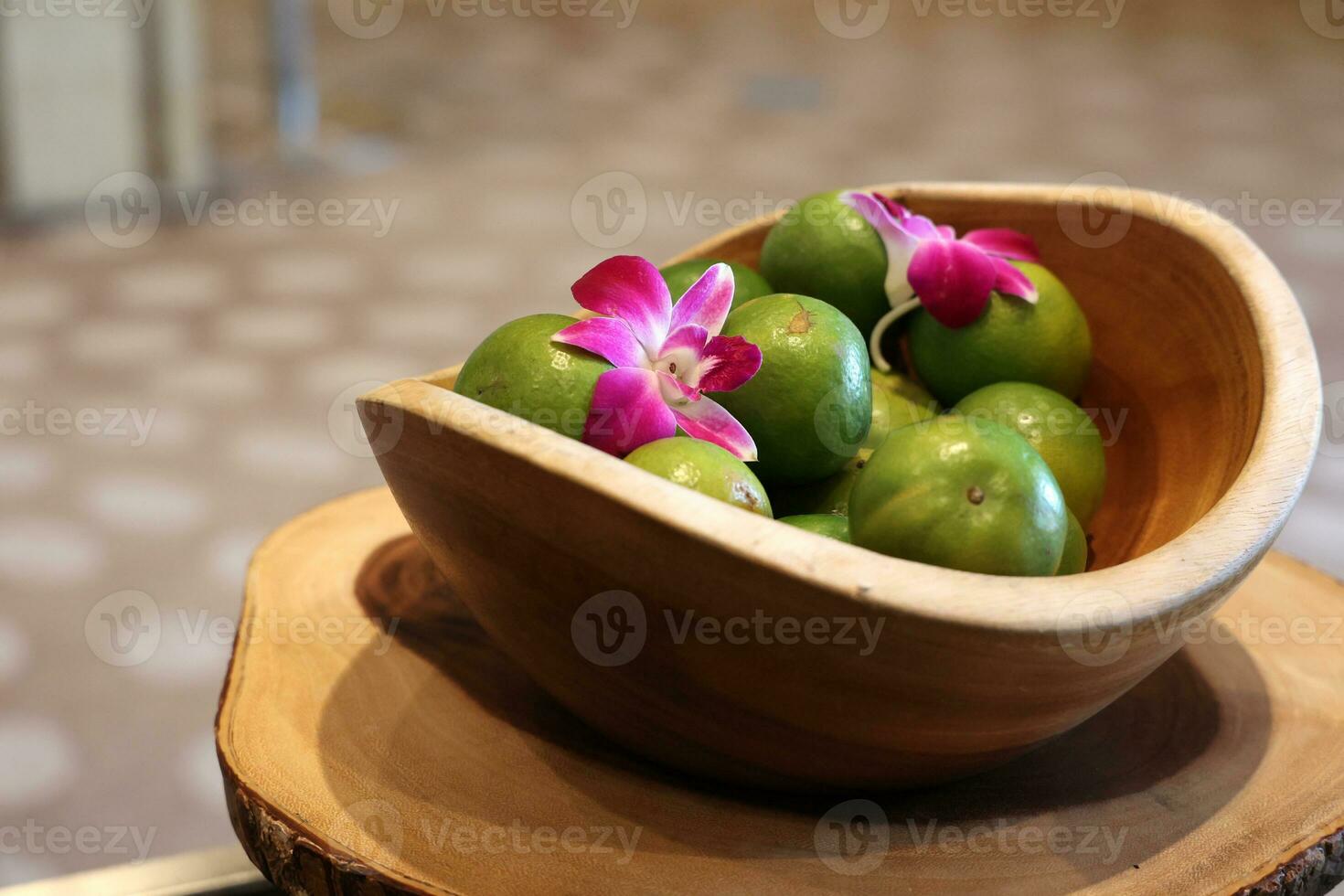 fruit in wooden bowl with pink orchids on table photo