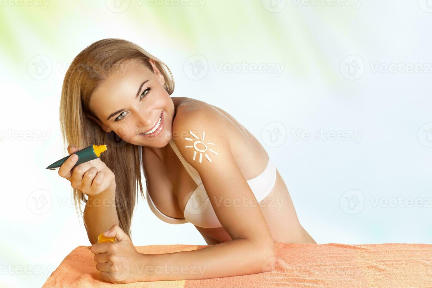 Happy woman applying sunscreen photo