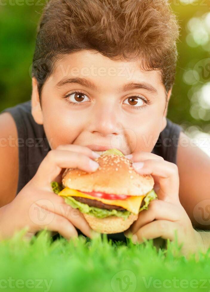 hambriento chico comiendo hamburguesa foto