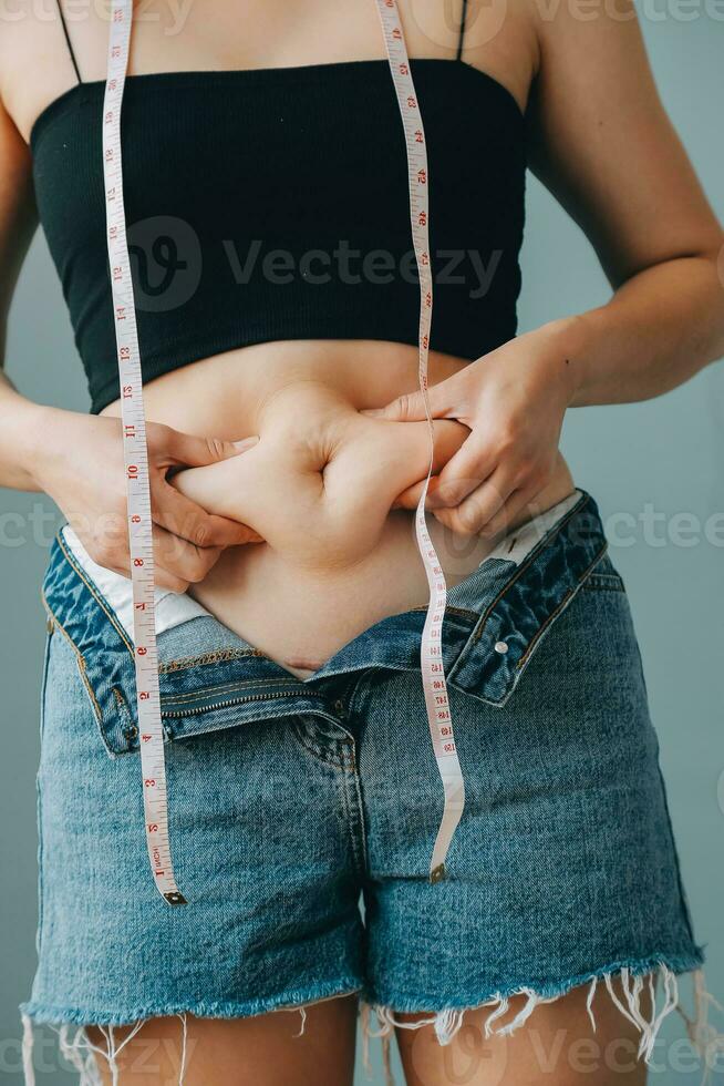 mujer gorda, barriga gorda, gordita, mujer obesa mano sosteniendo grasa abdominal excesiva con cinta métrica, concepto de estilo de vida de dieta de mujer foto