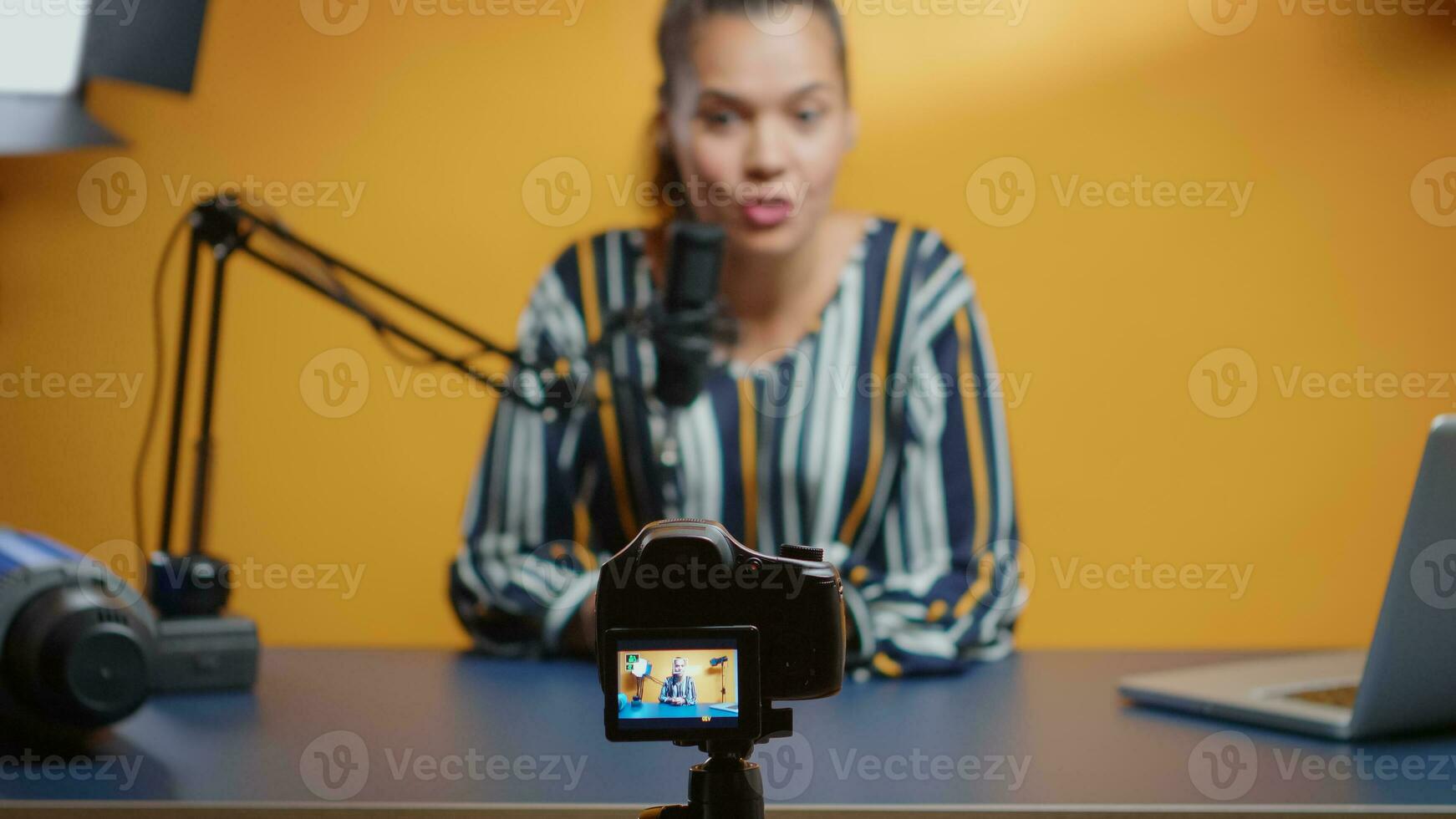 Selective focus on camera while social media star records an new podcast episode in her professional studio. Content creator new media influencer recording for internet web online subscribers audience photo